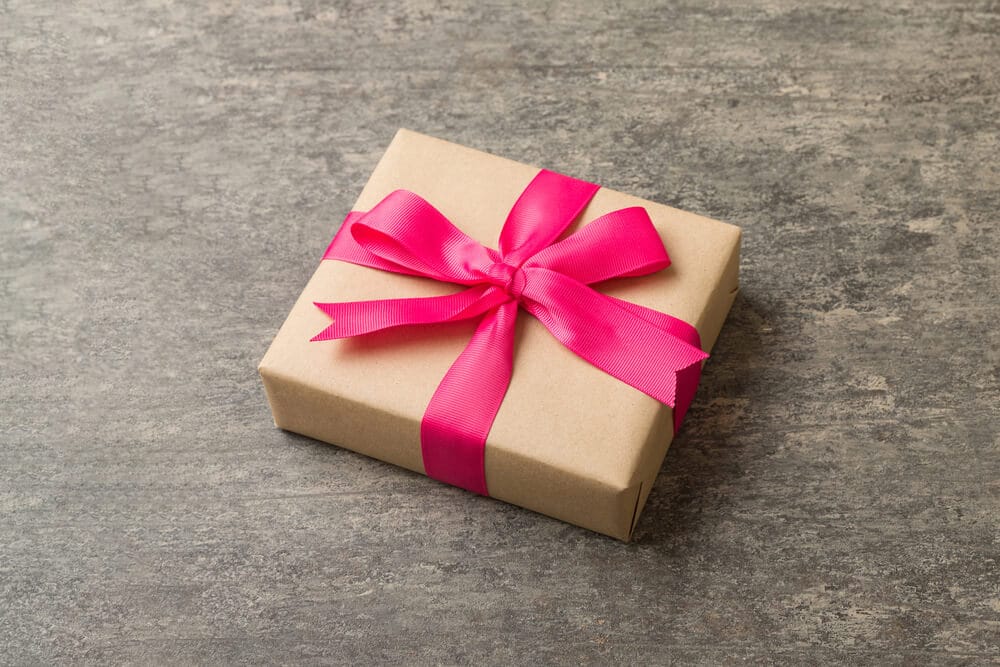 A small gift wrapped with a pink bow.