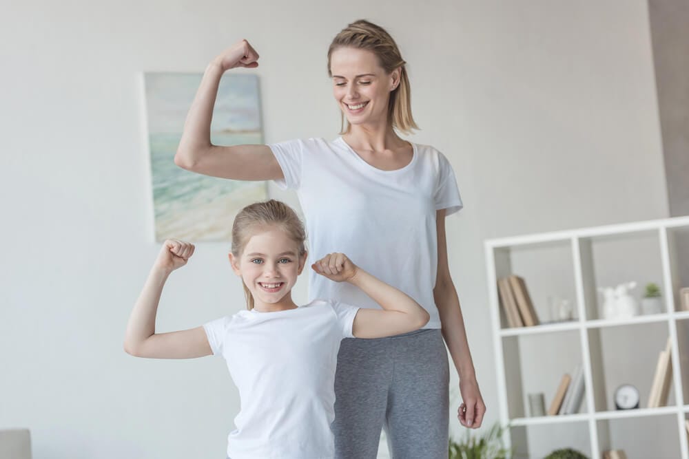 A woman and her daughter flex their muscles.